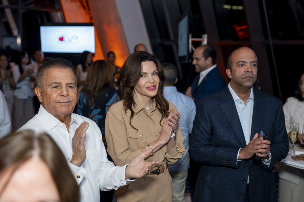 Invitados aplauden de pie en primera fila durante la presentacion.