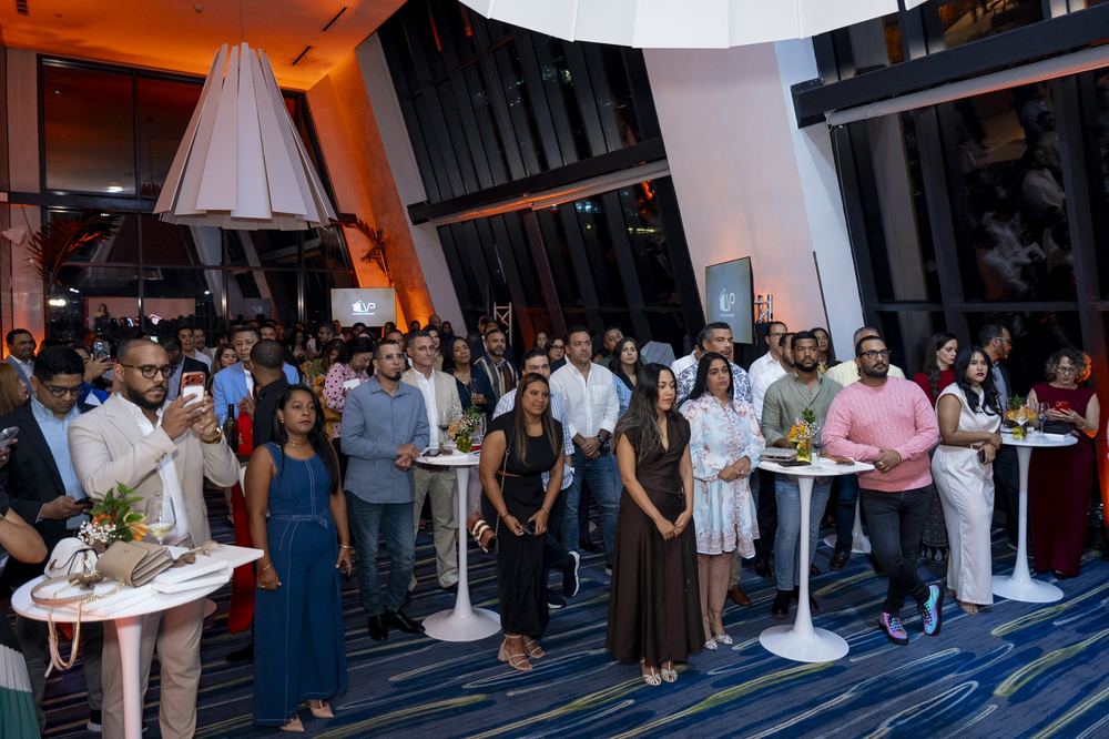 Salón lleno de invitados alrededor de mesas altas durante el lanzamiento inmobiliario.