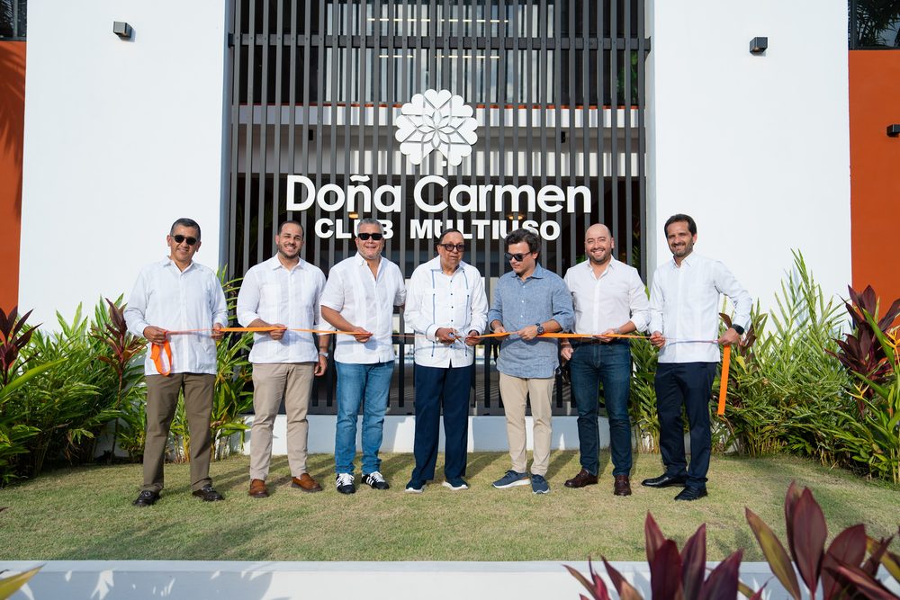 Directivos alineados sosteniendo la cinta naranja antes del corte inaugural.