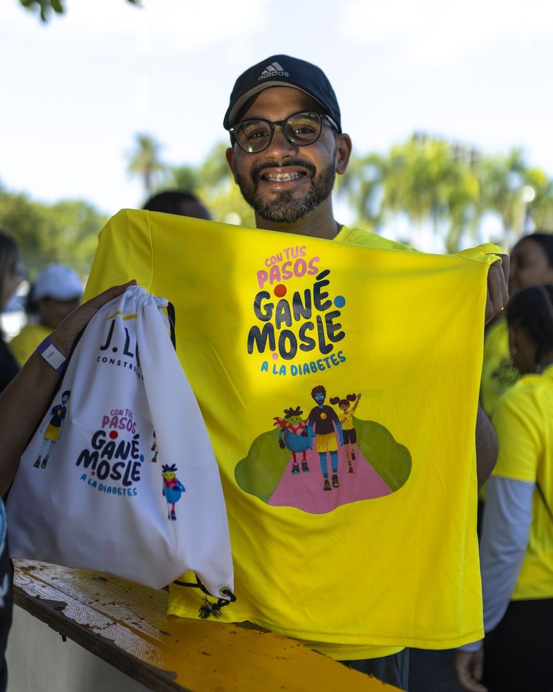 Participante sonriente sostiene en alto la camiseta oficial de la jornada.