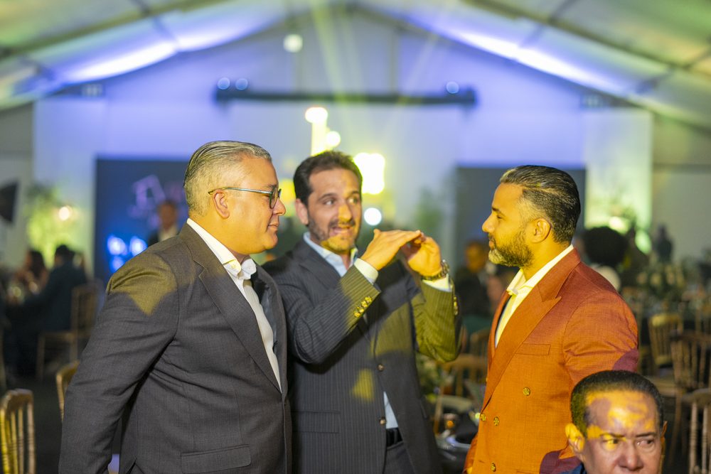 Directivos conversando durante la gala bajo la luz azul de la carpa.