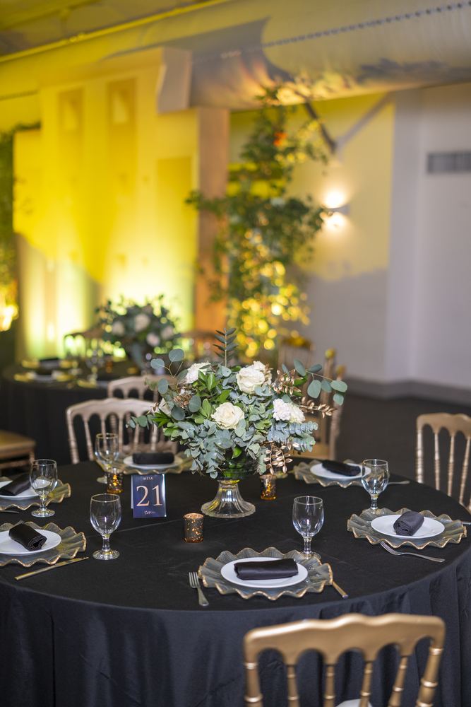 Mesa montada para la gala LVP Sales Awards con centro floral blanco y luz cálida de fondo.