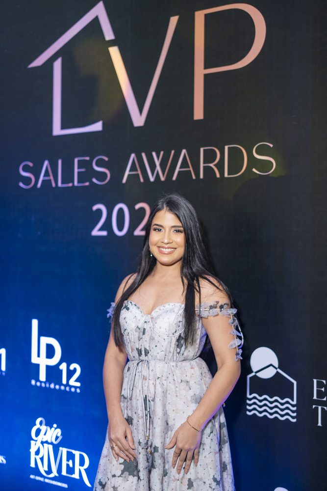 Invitada posando ante el backdrop iluminado de Sales Awards 2025.