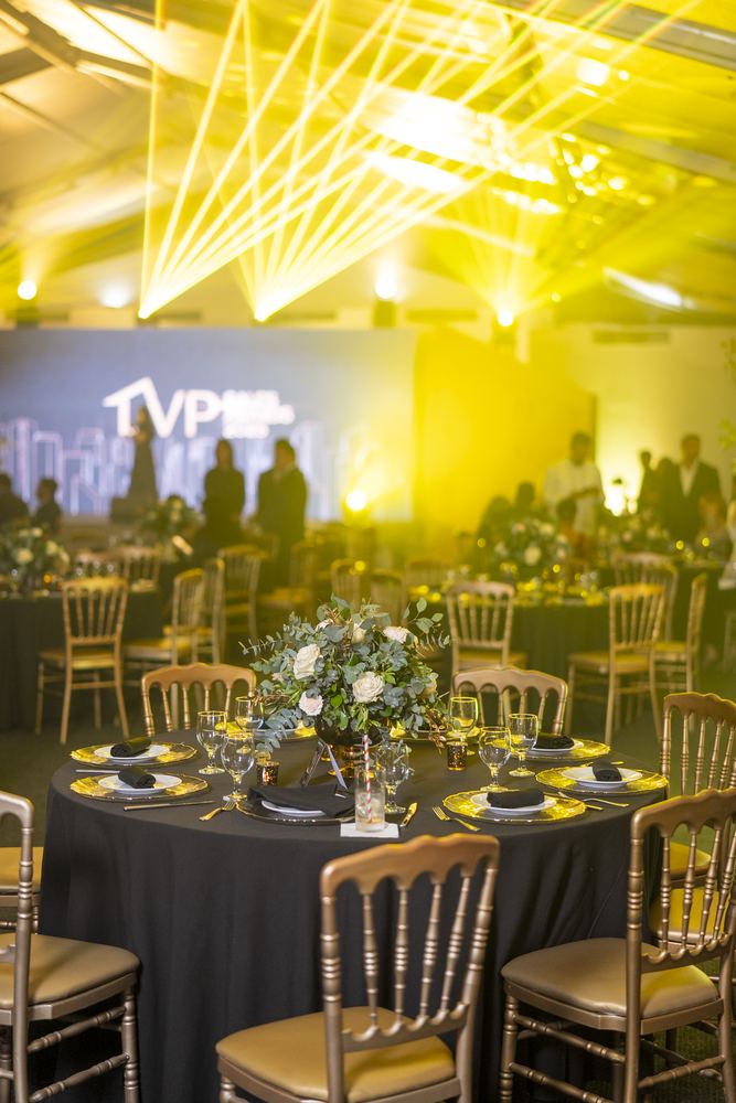 Vista general del salón de la gala con iluminación dorada y montaje de mesas.