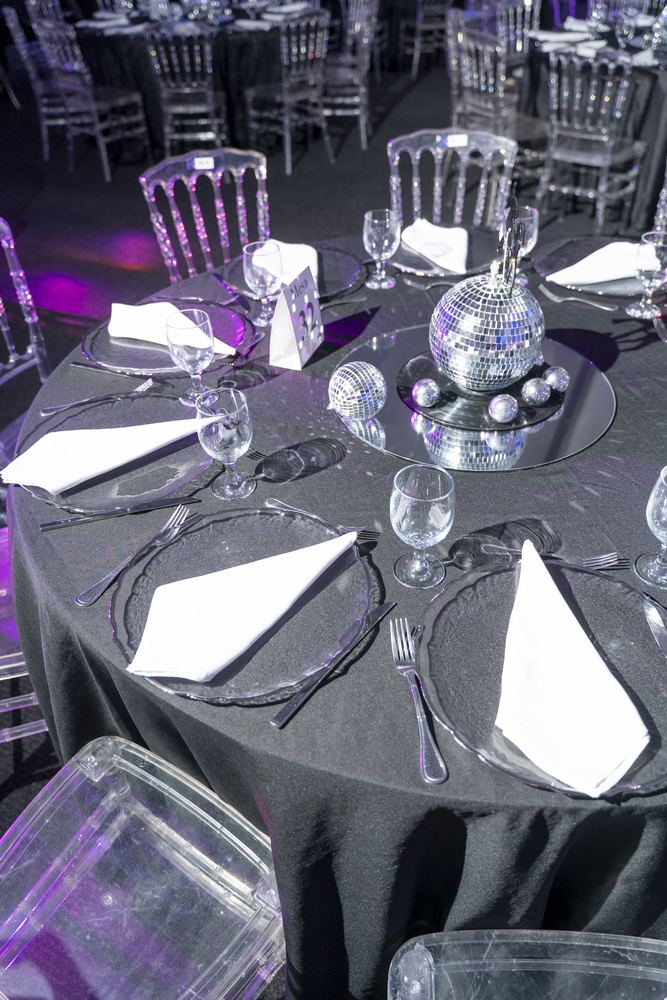 Detalle del centro de mesa con esferas espejadas sobre mantel negro y servilletas blancas.