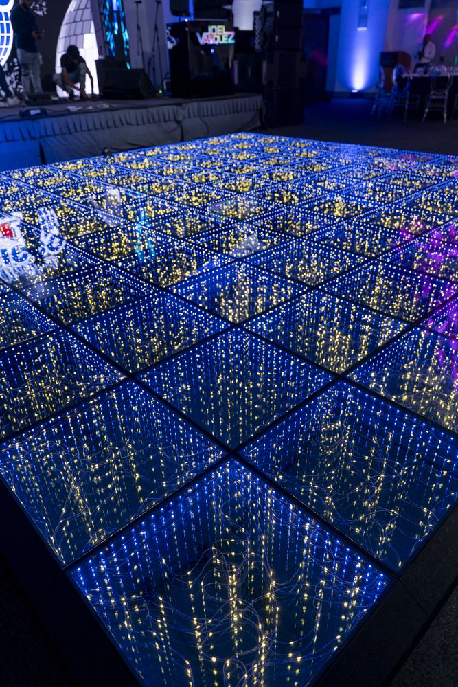 Pista de baile cubierta de luces azules y doradas formando un patrón geométrico.