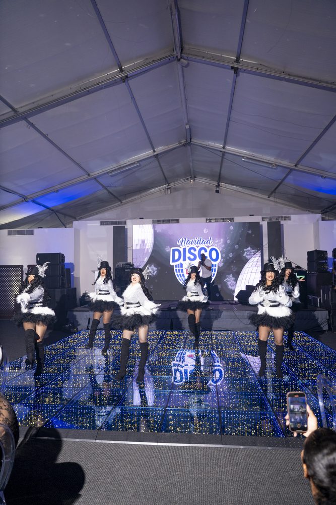 Cuerpo de baile en escena sobre la pista de luces del salón.