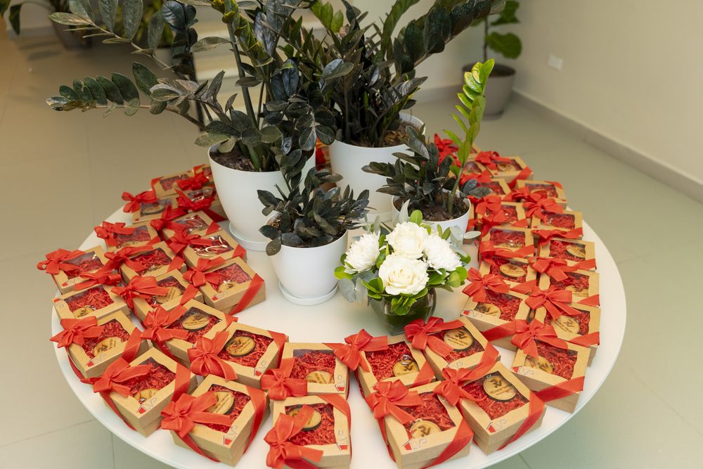 Mesa de obsequios con cajas envueltas en lazos rojos y arreglos verdes.