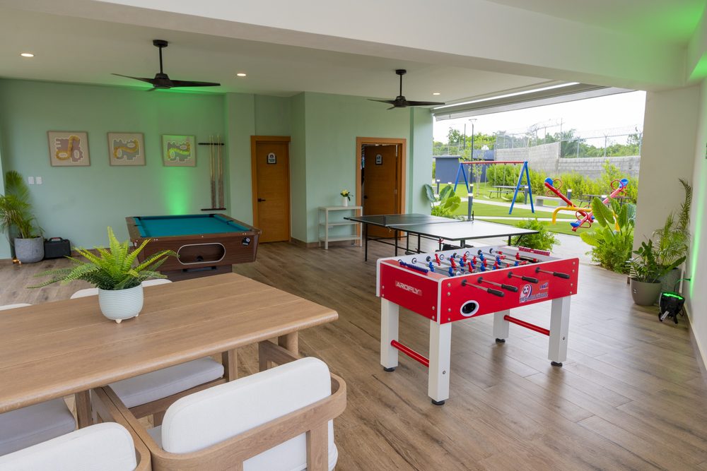 Salon de juegos de la casa club con billar y futbolin bajo luz verde.