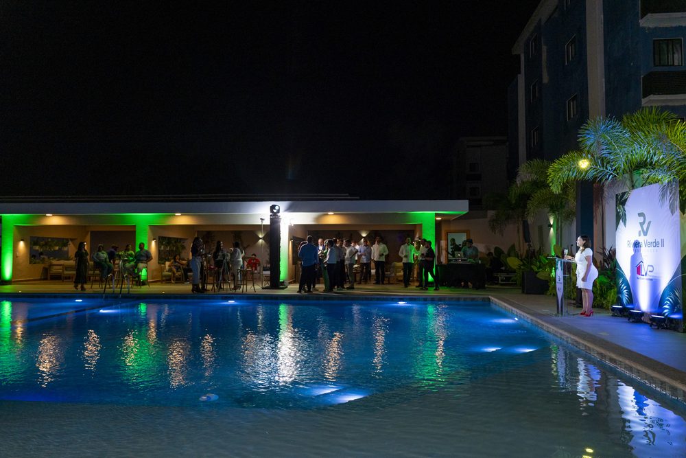 La piscina de noche con la casa club iluminada al fondo.