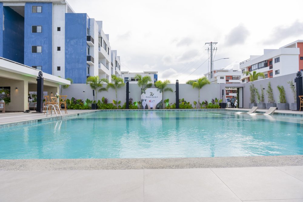 Piscina de la casa club rodeada por los edificios del residencial al atardecer.